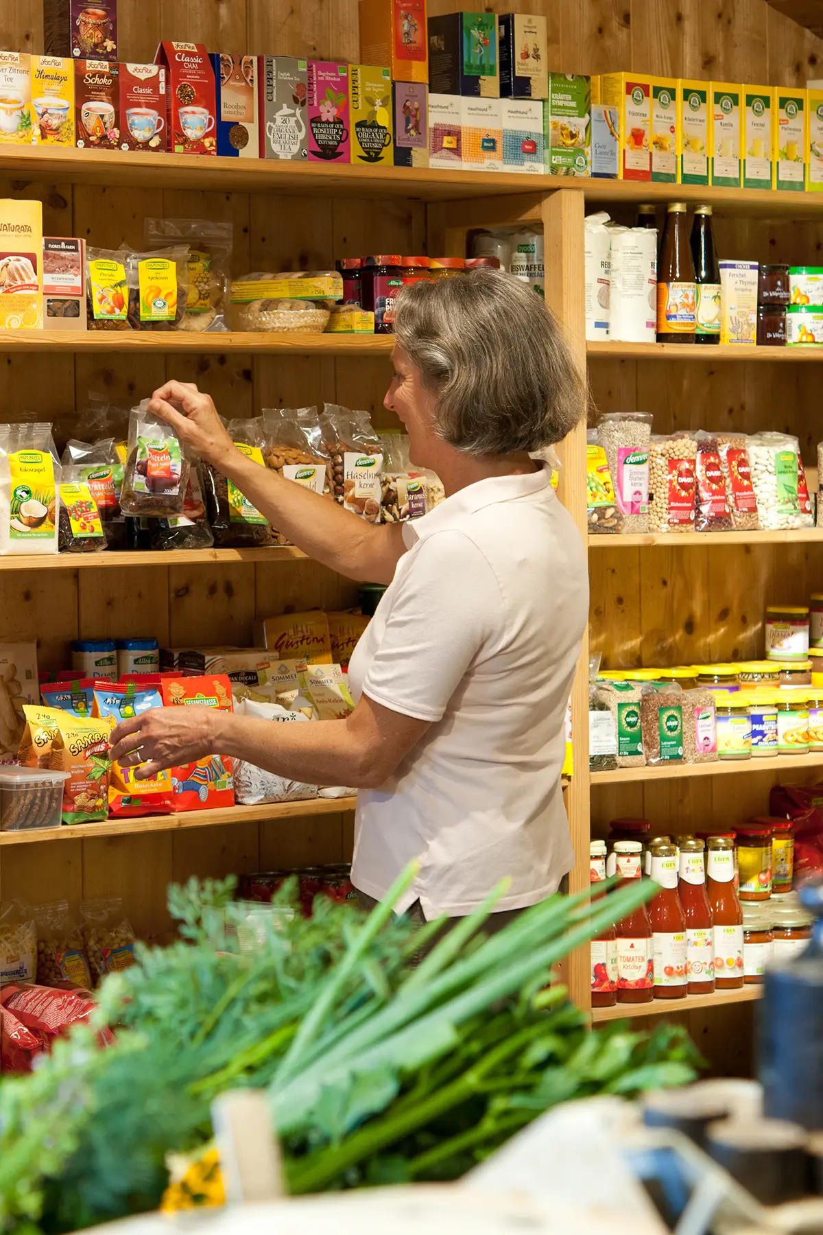 Mitarbeiterin im Hofladen der Pummerer Biokiste in Riedering beim Einsortieren von Bio-Produkten und regionalen Lebensmitteln.